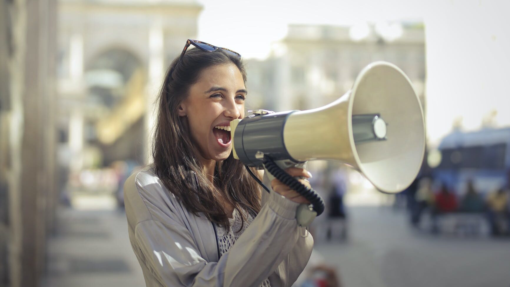 cheerful young woman screaming into megaphone