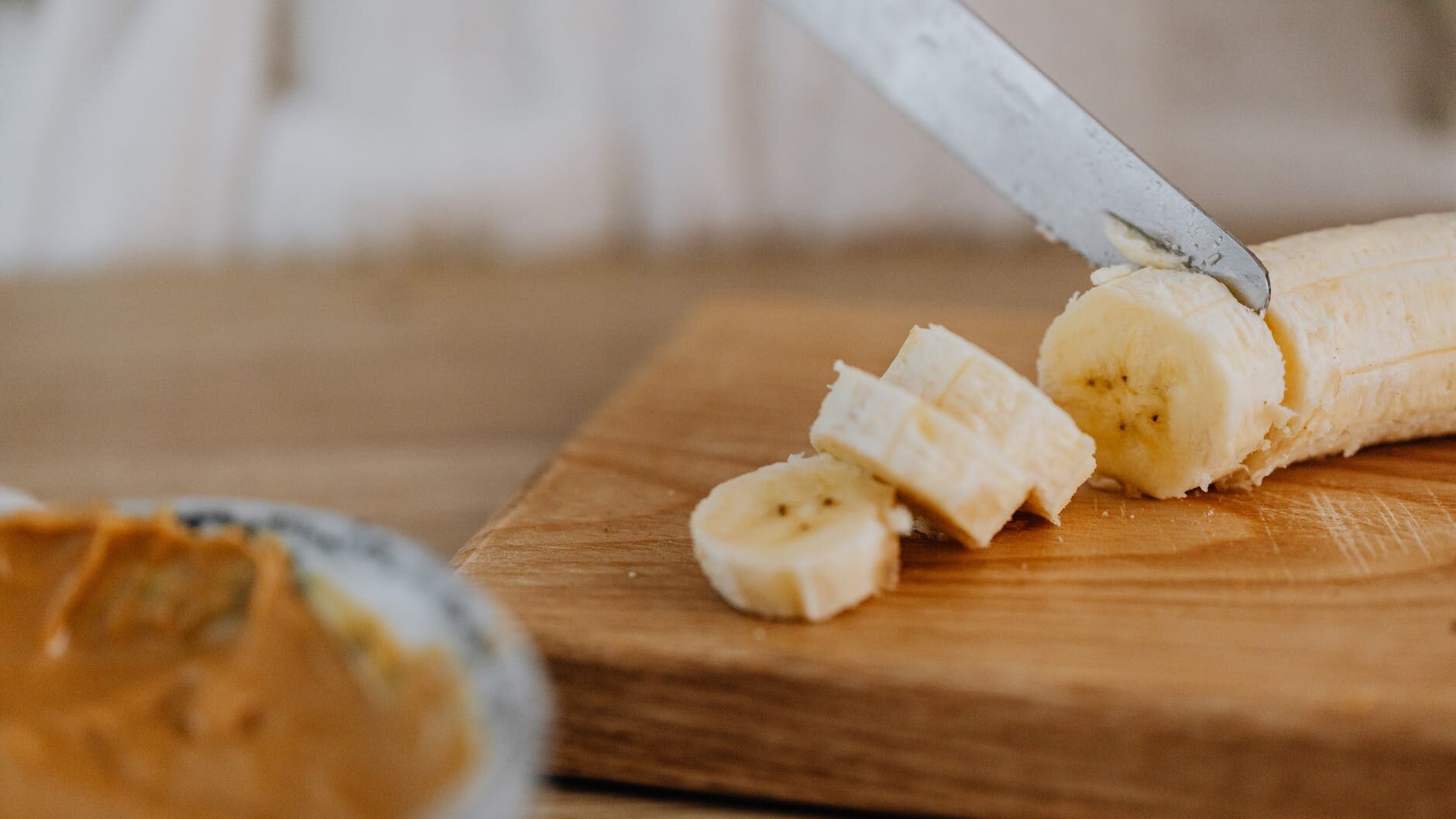 slicing of banana on wooden chopping board