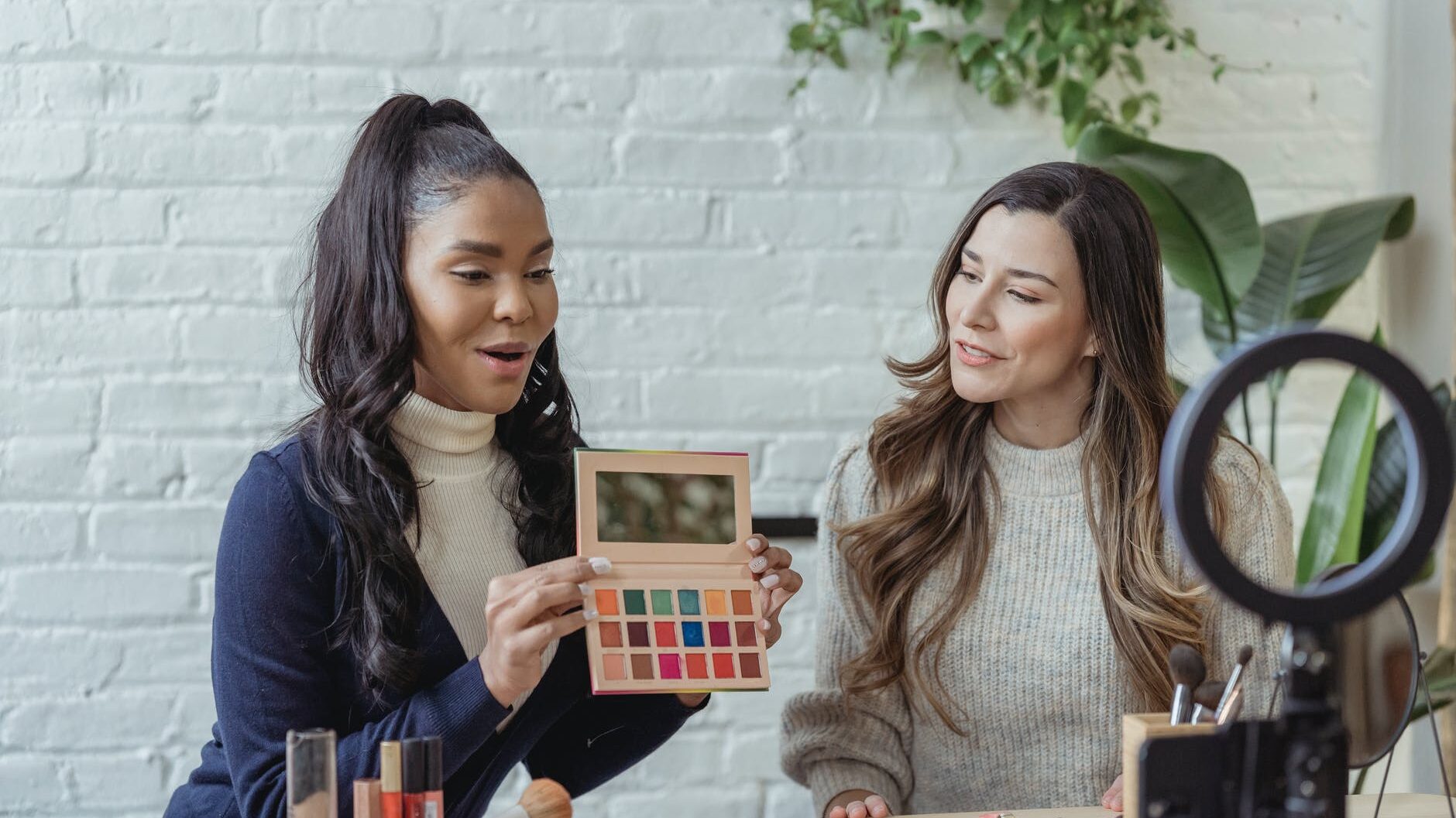 young diverse ladies recording vlog about makeup products on smartphone