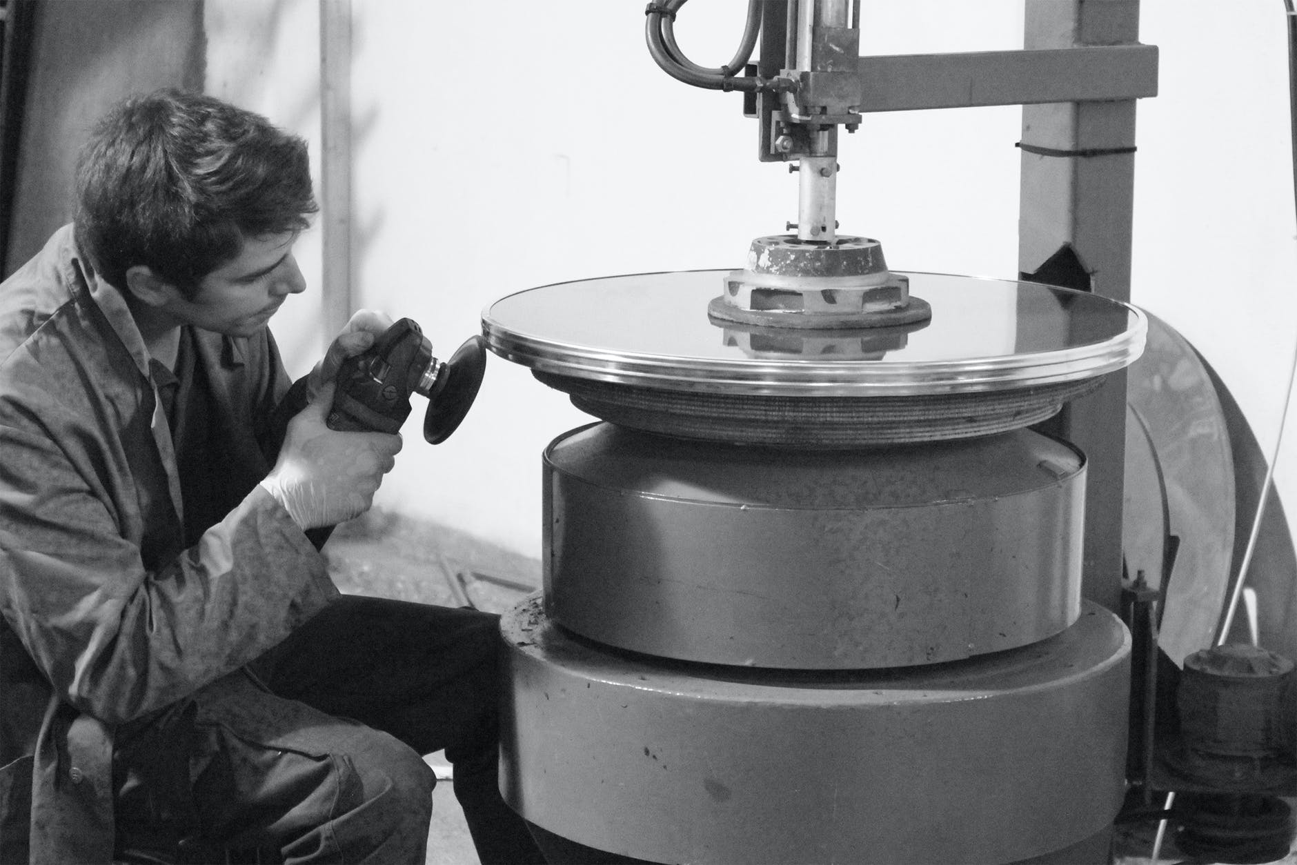 man sanding on metal surface in grayscale photography